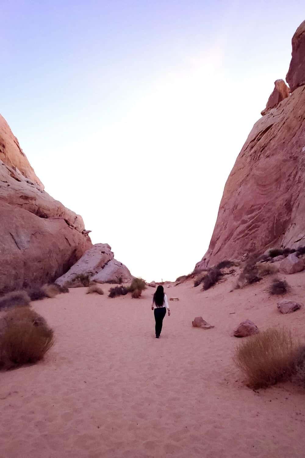 Girl walking on sand between high rocks in Valley of Fire State Park