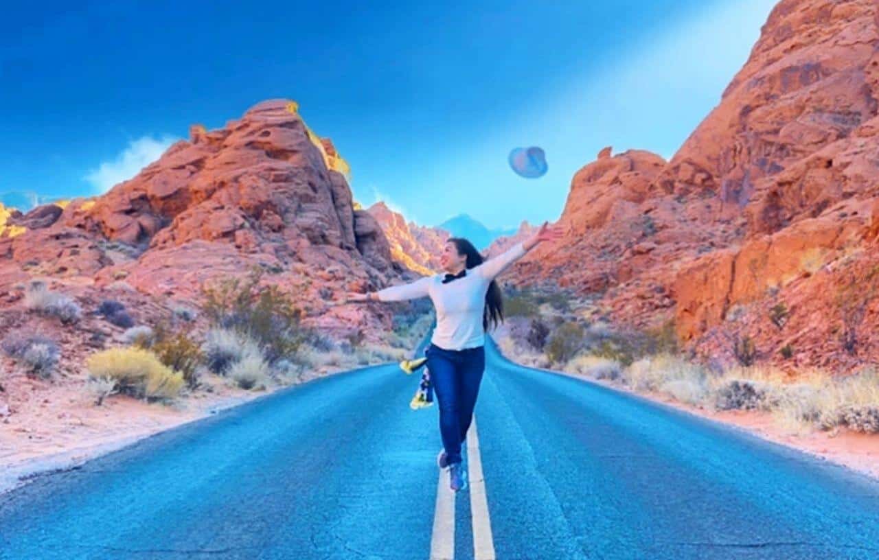 Girl jumping and throwing white hat in the middle of the road on White Domes Road at Valley of Fire State Park